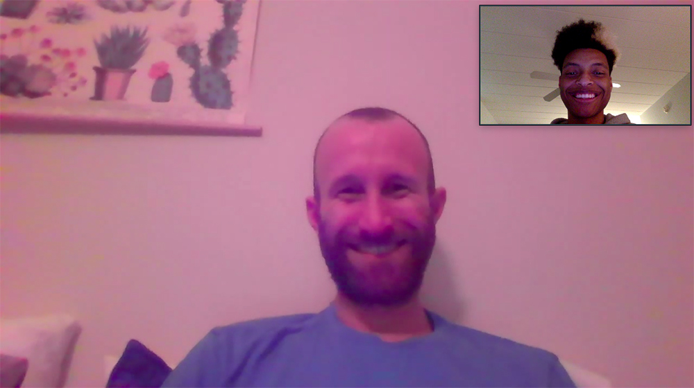 Two men smiling while talking over Zoom.
